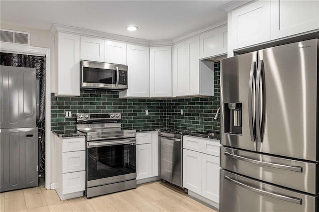 600 Oakmont Hl, Duluth, GA 30097 - kitchen featuring stainless steel appliances, stacked washer / drying machine, white cabinets, decorative backsplash, and light wood-style flooring