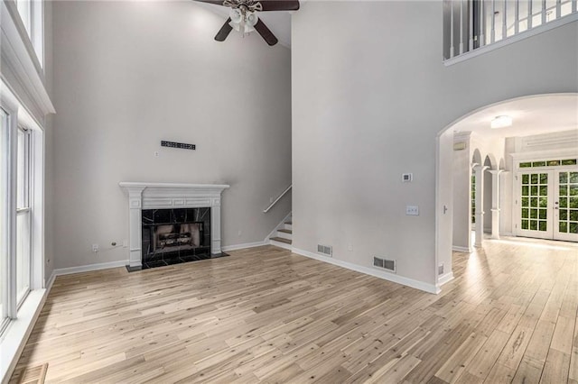 600 Oakmont Hl, Duluth, GA 30097 - unfurnished living room featuring a high ceiling, arched walkways, a ceiling fan, light wood-style floors, and a premium fireplace