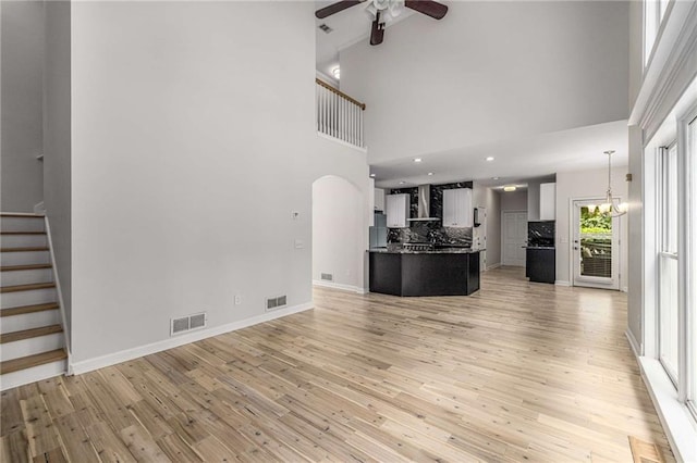 600 Oakmont Hl, Duluth, GA 30097 - unfurnished living room with a ceiling fan, a high ceiling, light wood-style floors, stairs, and arched walkways