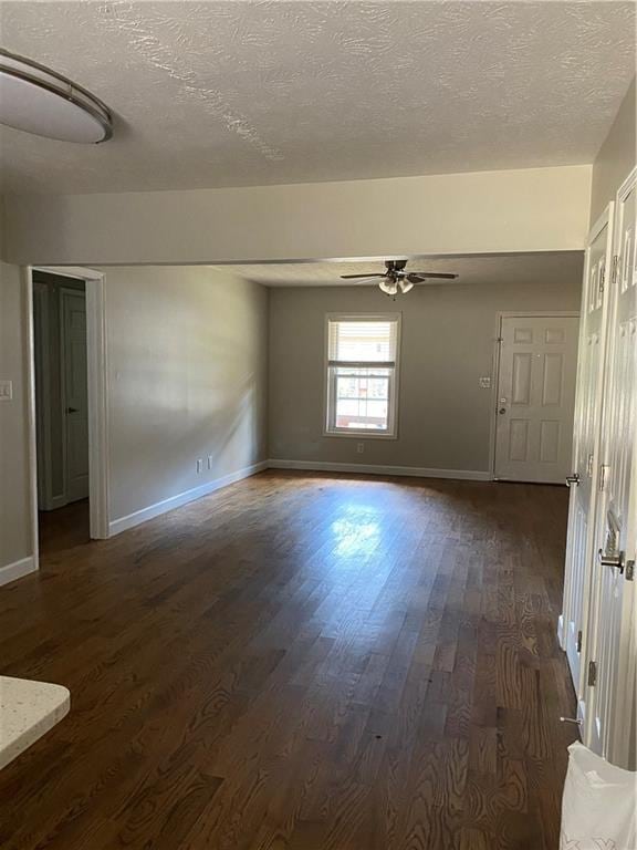 empty room featuring ceiling fan, dark wood-type flooring, and a textured ceiling