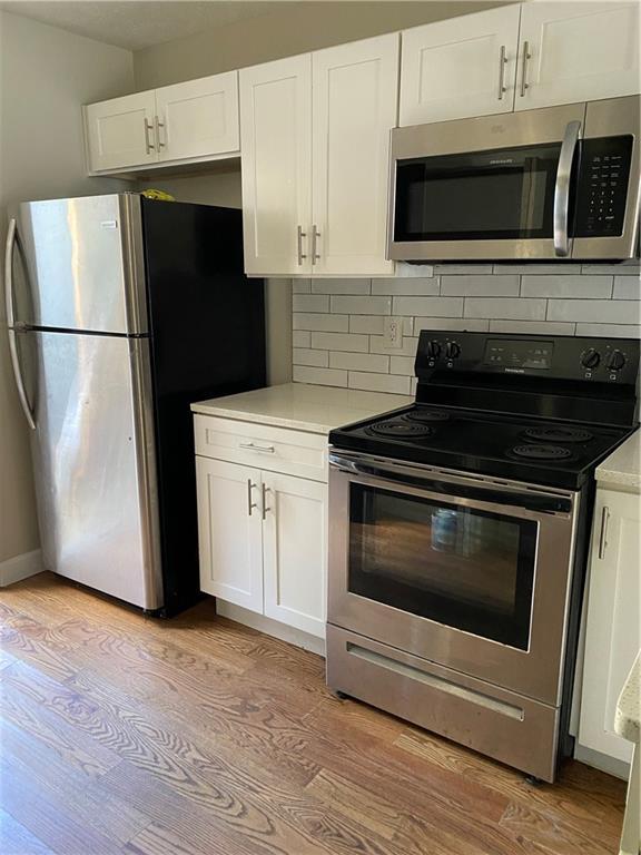 kitchen featuring white cabinetry, appliances with stainless steel finishes, and light hardwood / wood-style flooring