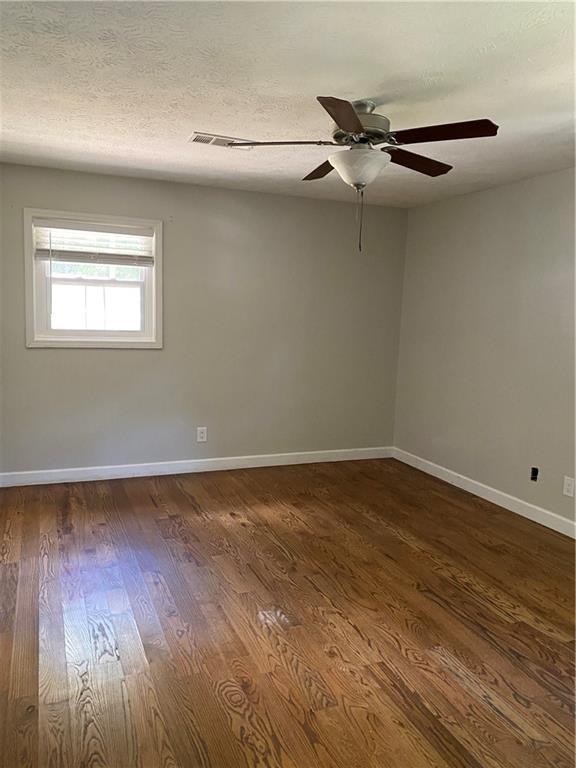 empty room with ceiling fan, dark hardwood / wood-style flooring, and a textured ceiling