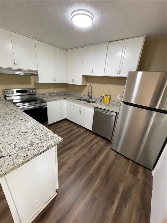 6399 Boca Grande Blvd, Forest Park, GA 30297 - kitchen featuring appliances with stainless steel finishes, under cabinet range hood, white cabinetry, a sink, and a textured ceiling