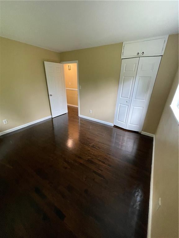 6399 Boca Grande Blvd, Forest Park, GA 30297 - unfurnished bedroom featuring dark wood finished floors, baseboards, and a closet