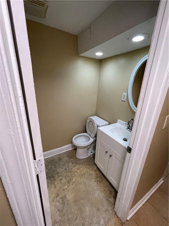 6399 Boca Grande Blvd, Forest Park, GA 30297 - half bathroom with toilet, vanity, baseboards, and recessed lighting