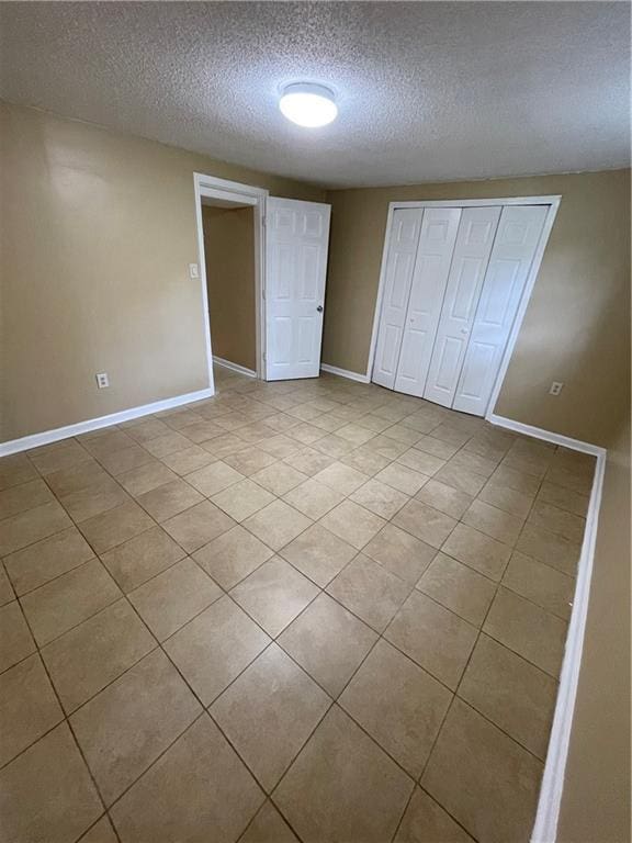 6399 Boca Grande Blvd, Forest Park, GA 30297 - unfurnished bedroom featuring a textured ceiling, baseboards, light tile patterned floors, and a closet