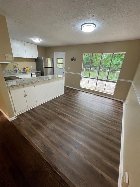 6399 Boca Grande Blvd, Forest Park, GA 30297 - kitchen featuring stainless steel appliances, dark wood-style flooring, a textured ceiling, a peninsula, and white cabinetry