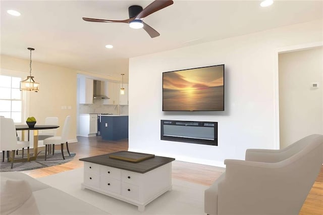 living room featuring light hardwood / wood-style flooring and ceiling fan with notable chandelier