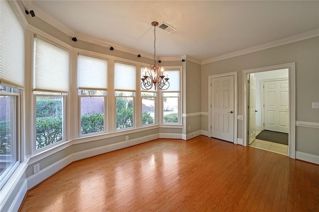 unfurnished dining area with hardwood / wood-style floors, crown molding, and a chandelier