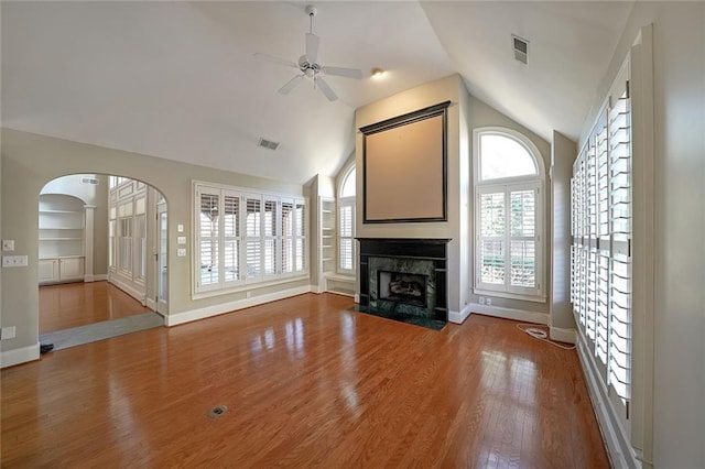 unfurnished living room featuring hardwood / wood-style floors, a high end fireplace, lofted ceiling, built in shelves, and ceiling fan