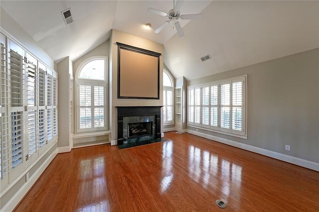 unfurnished living room featuring vaulted ceiling, wood-type flooring, a fireplace, and plenty of natural light