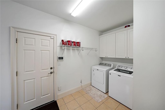 clothes washing area featuring washer and dryer, cabinets, and light tile patterned floors