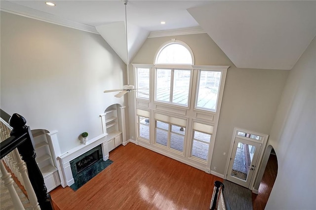 living room featuring ceiling fan, vaulted ceiling, hardwood / wood-style floors, ornamental molding, and a high end fireplace