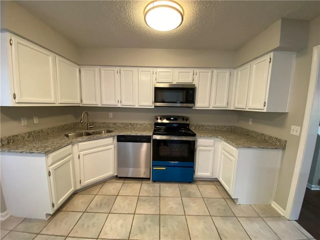 kitchen featuring stainless steel appliances, white cabinetry, a textured ceiling, light stone countertops, and sink