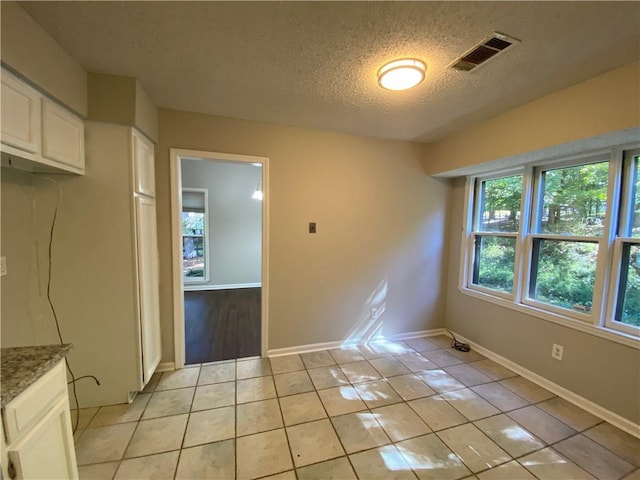 unfurnished dining area with a textured ceiling and light tile patterned floors