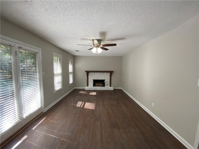 unfurnished living room featuring a fireplace, dark wood-type flooring, a textured ceiling, and ceiling fan