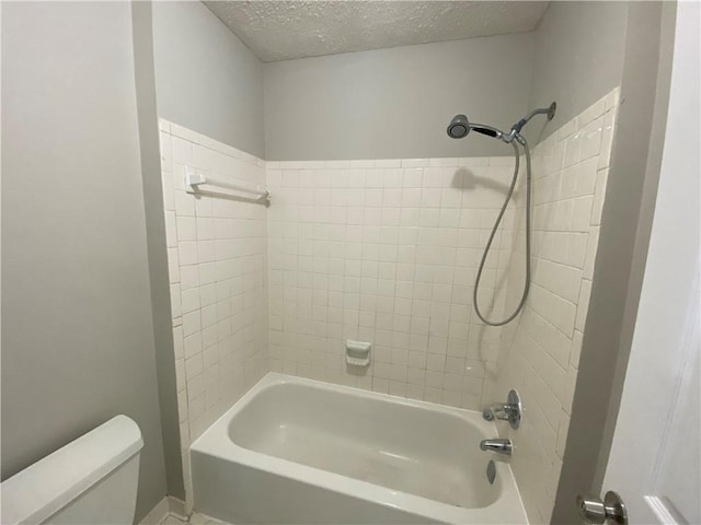 bathroom with tiled shower / bath, toilet, and a textured ceiling