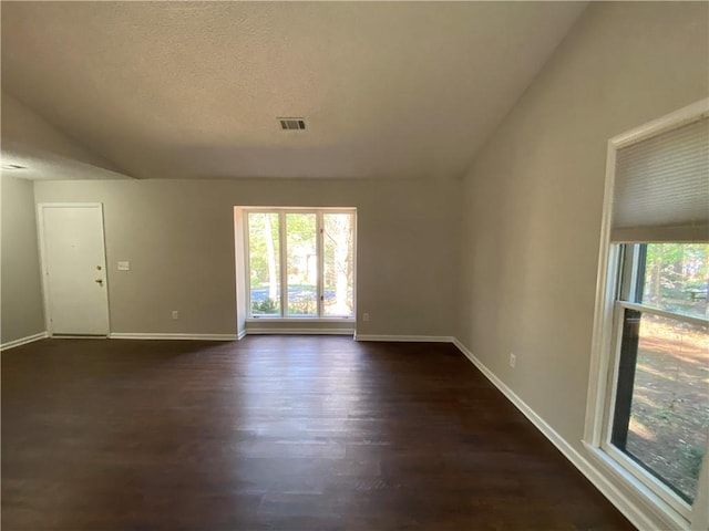 empty room featuring a textured ceiling and dark hardwood / wood-style flooring