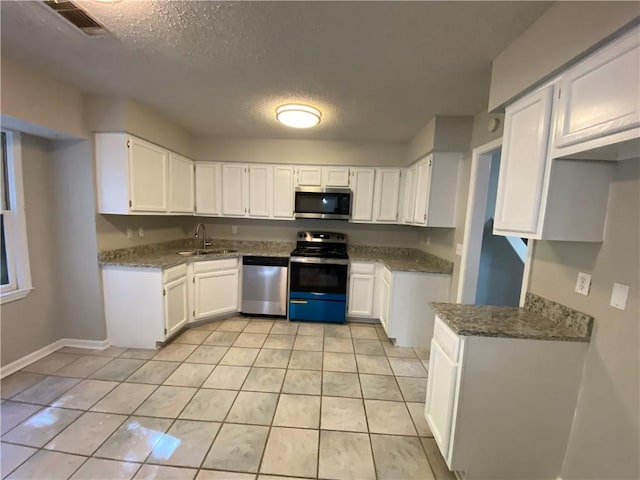 kitchen featuring white cabinetry, appliances with stainless steel finishes, dark stone counters, and light tile patterned floors