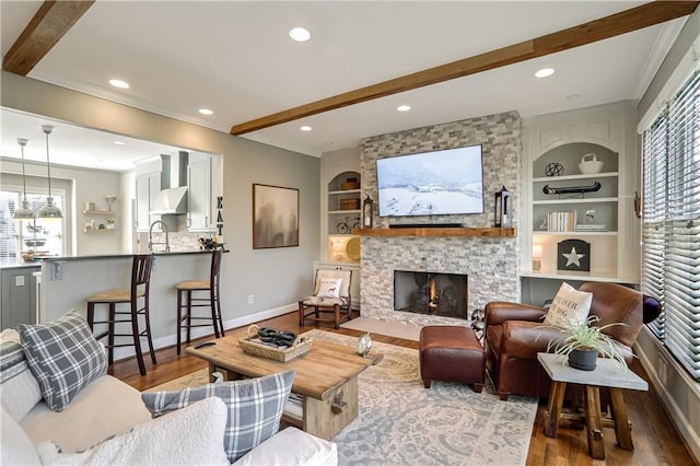 living room featuring crown molding, wood finished floors, beam ceiling, and baseboards