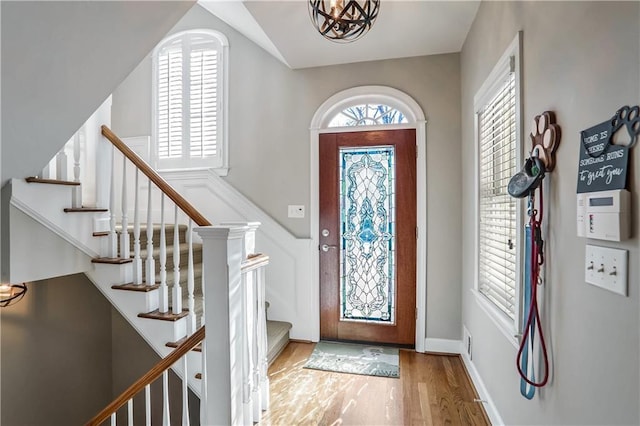 entryway with vaulted ceiling, plenty of natural light, wood finished floors, and baseboards