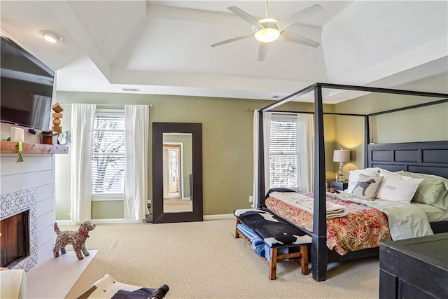 carpeted bedroom featuring a tile fireplace, multiple windows, vaulted ceiling, and visible vents