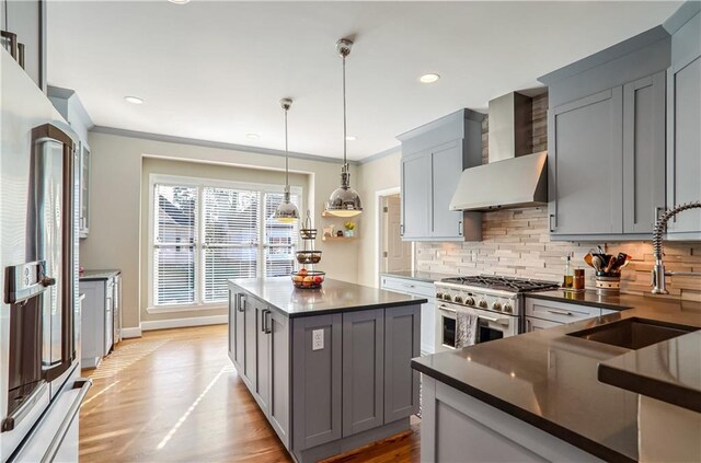 kitchen featuring pendant lighting, wall chimney exhaust hood, high quality appliances, and gray cabinets