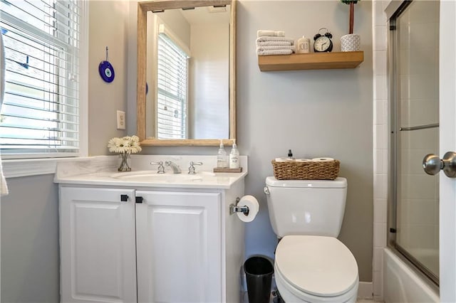 bathroom featuring toilet, plenty of natural light, bath / shower combo with glass door, and vanity