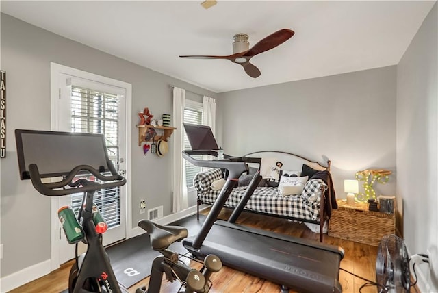 exercise room with baseboards, wood finished floors, visible vents, and a ceiling fan