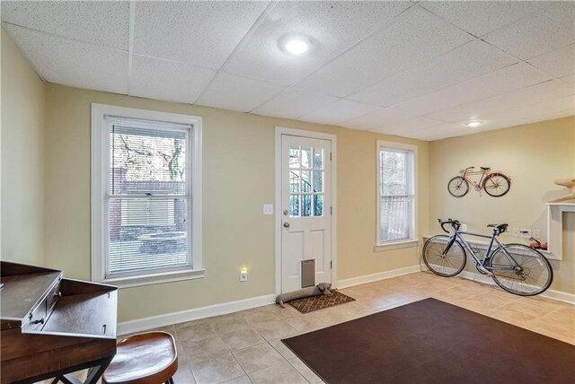 doorway with a healthy amount of sunlight, light tile patterned floors, and a paneled ceiling