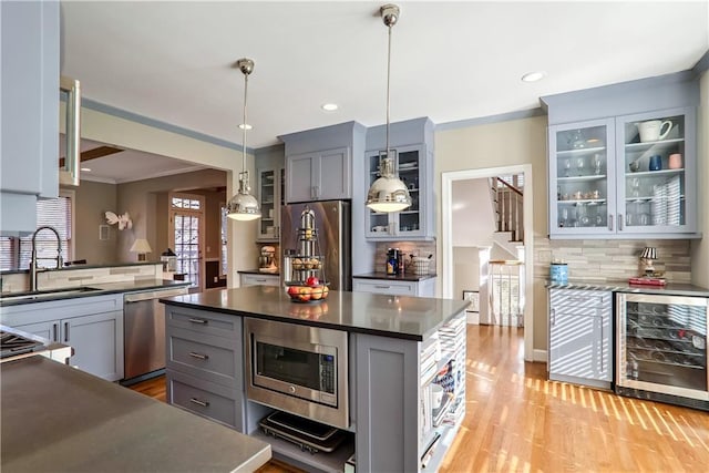 kitchen featuring appliances with stainless steel finishes, decorative light fixtures, sink, wine cooler, and a center island