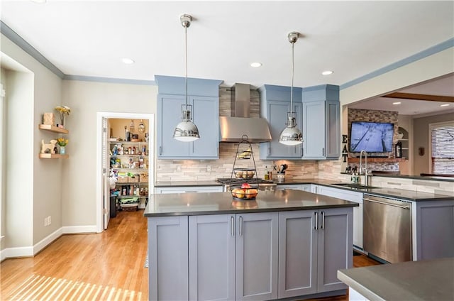 kitchen with stainless steel appliances, wall chimney range hood, dark countertops, and decorative light fixtures