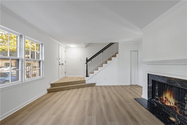 entryway with ornamental molding, a fireplace, and light hardwood / wood-style floors