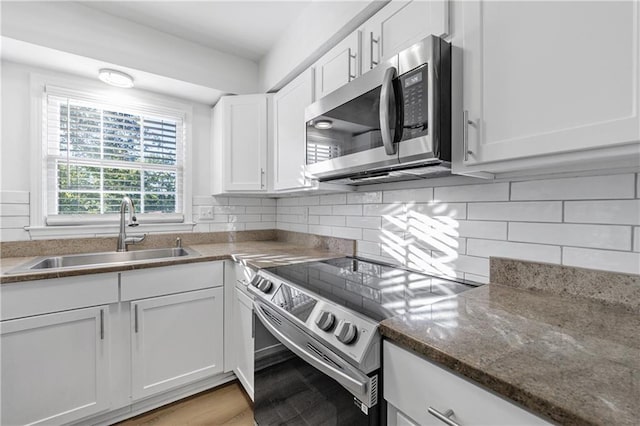 kitchen with white cabinetry, appliances with stainless steel finishes, sink, and decorative backsplash