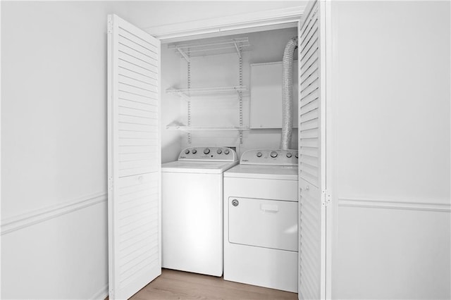 clothes washing area with independent washer and dryer and light hardwood / wood-style flooring