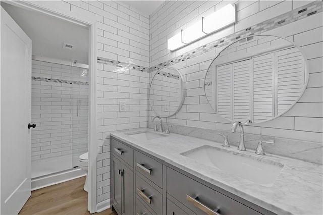 bathroom featuring toilet, wood-type flooring, tile walls, vanity, and a shower with door