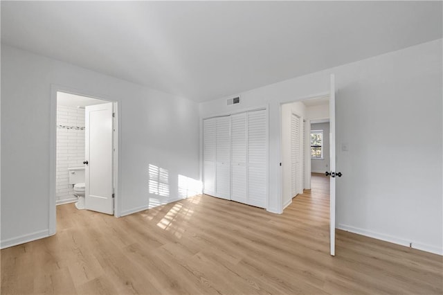 unfurnished bedroom featuring ensuite bath and light hardwood / wood-style floors