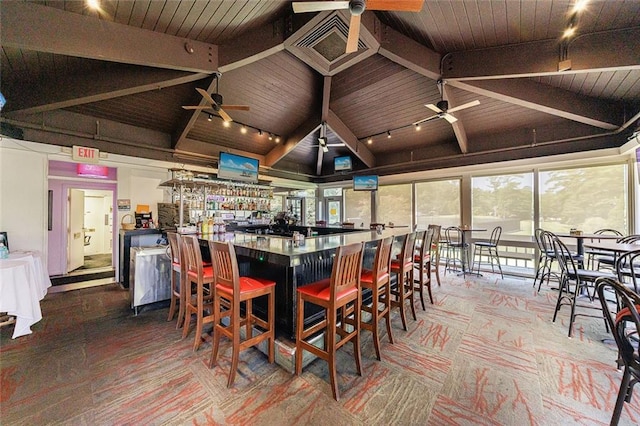 dining area with vaulted ceiling with beams, track lighting, wooden ceiling, and indoor bar