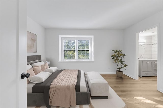 bedroom with light hardwood / wood-style floors and ensuite bathroom