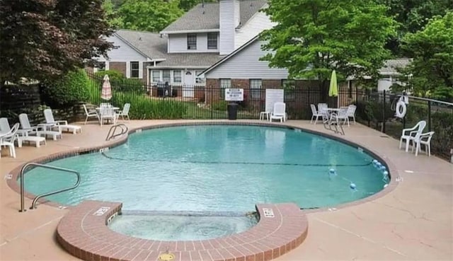 view of swimming pool featuring a patio and a hot tub