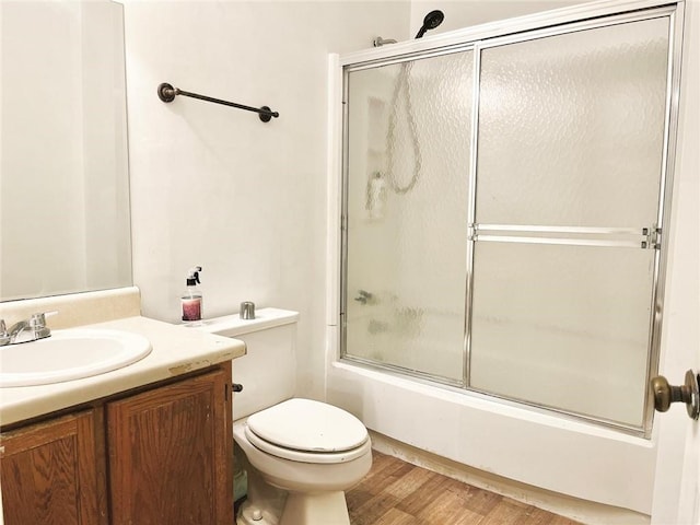 full bathroom featuring toilet, hardwood / wood-style floors, vanity, and combined bath / shower with glass door