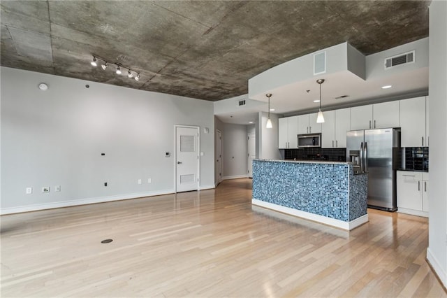 kitchen with white cabinetry, light hardwood / wood-style flooring, hanging light fixtures, appliances with stainless steel finishes, and backsplash