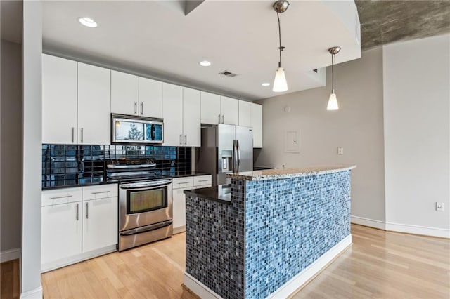 kitchen featuring pendant lighting, a kitchen island, white cabinets, and appliances with stainless steel finishes