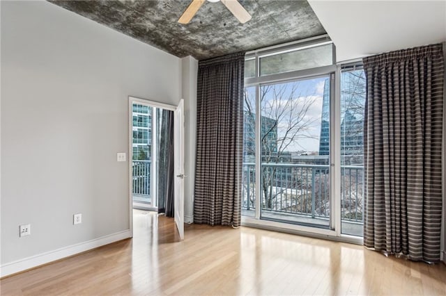 unfurnished room featuring expansive windows, ceiling fan, and light wood-type flooring