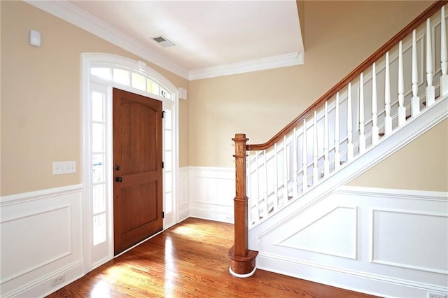 foyer entrance with a wealth of natural light, light hardwood / wood-style flooring, and ornamental molding