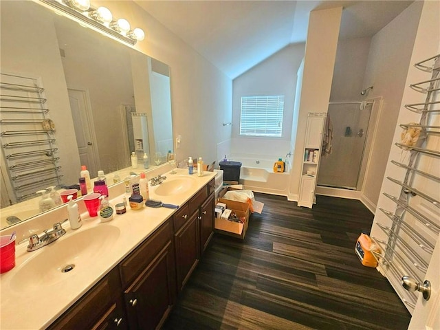 bathroom with a garden tub, lofted ceiling, a stall shower, double vanity, and wood finished floors