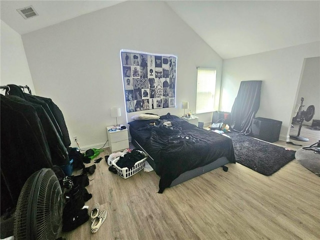 bedroom with wood finished floors, vaulted ceiling, and baseboards