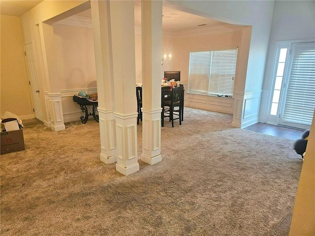 corridor featuring crown molding, carpet floors, a chandelier, a decorative wall, and wainscoting