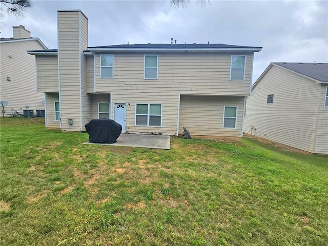 rear view of house featuring a patio, a yard, central air condition unit, and a chimney
