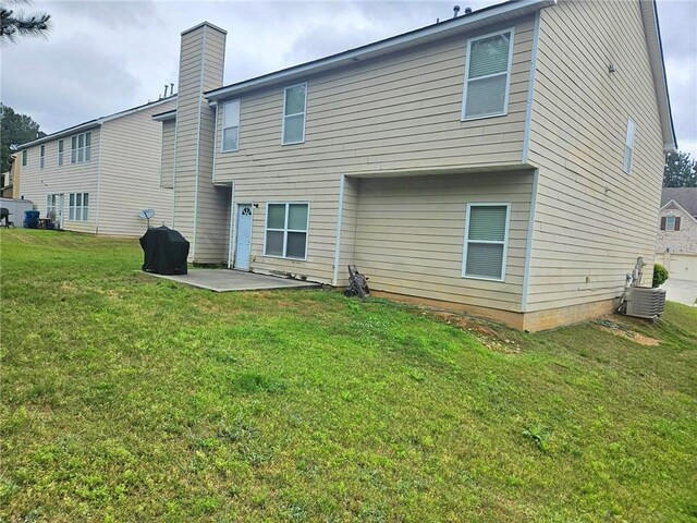 rear view of property featuring a patio, a yard, cooling unit, and a chimney